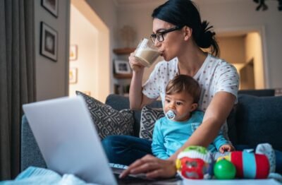 Working mum working from home drinking coffee balancing business and baby -female breadwinners mental load