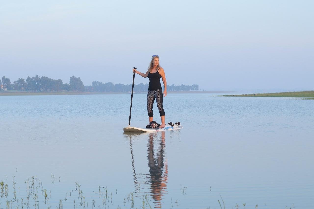 Alison Weihe paddleboarding on a calm lake, embracing fitness, freedom, and adventure by travelling in her 60s