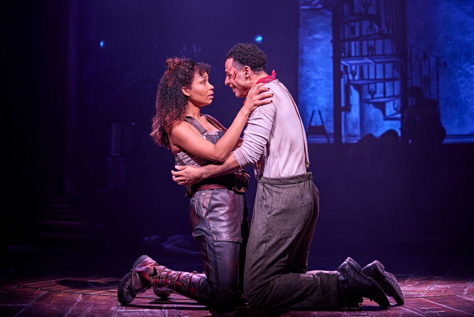 bethany antonia and marley fenton holding each other and kneeling on stage in hadestown.