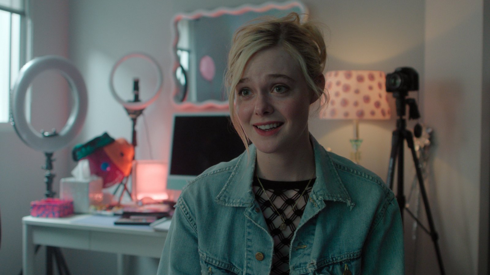 Elle Fanning smiling as Margo inside a room filled with tripods and ring lights in 'Margo's Got Money Troubles'.