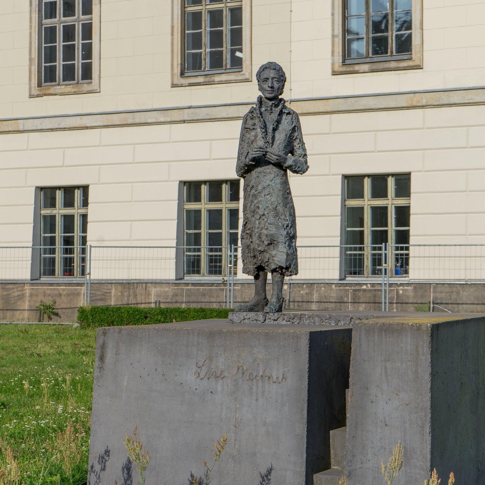 Photo of the grey statue monument to Lise Meitner in front of the Humboldt University in Berlin