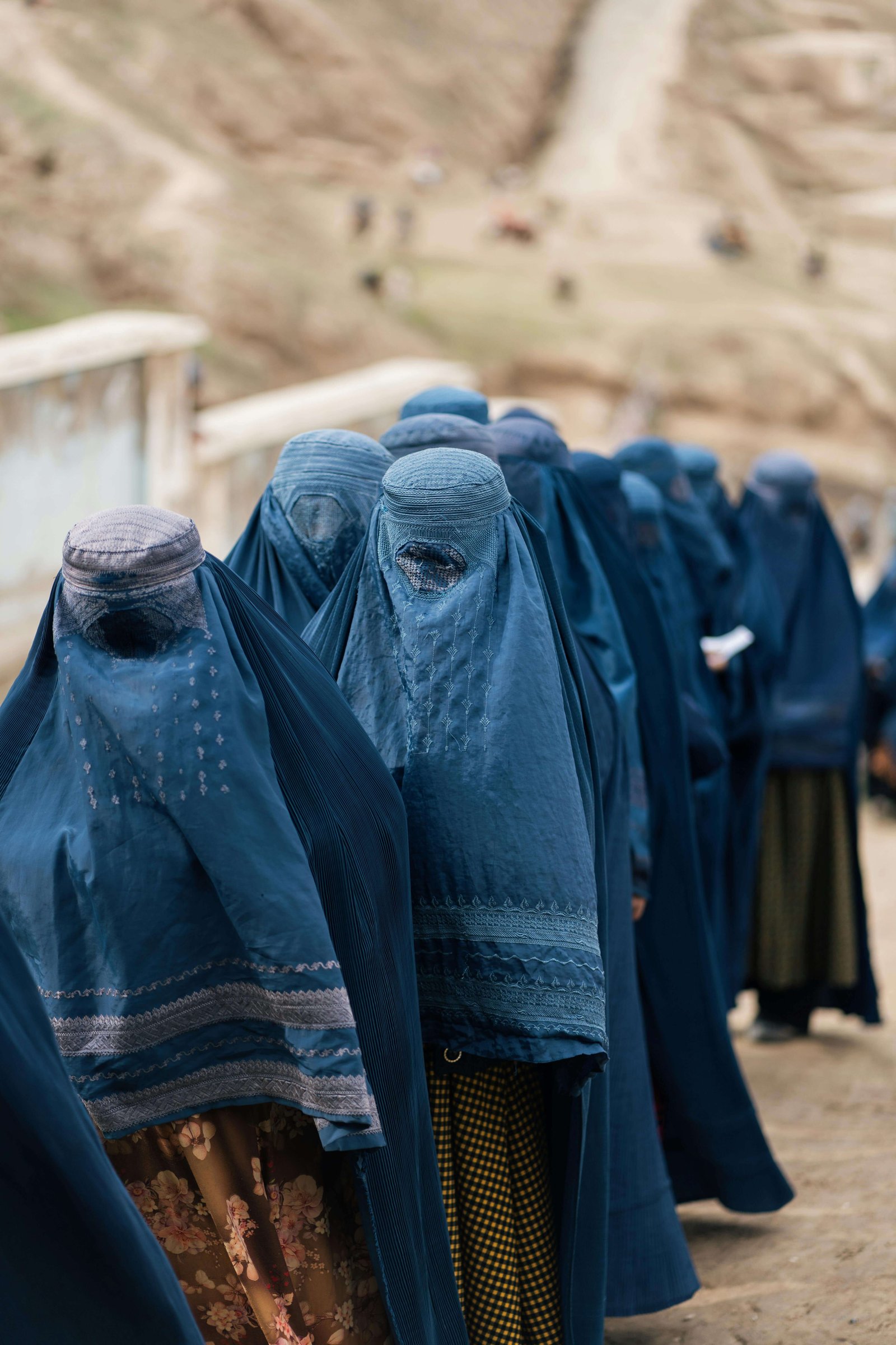 Afghan women wearing blue burqas stand in a line under Taliban rule, reflecting severe restrictions on women’s rights as Domestic abuse is legalised by Taliban in Afghanistan