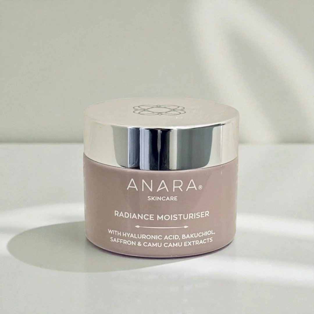 A jar of Anara Skincare Radiance Moisturiser, featuring a silver lid and beige body, placed on a light surface