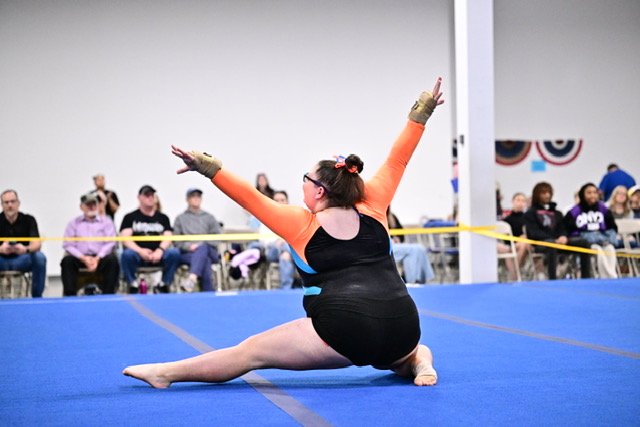 Angela Salvatore performs a pose during her floor routine at a gymnastics competition.