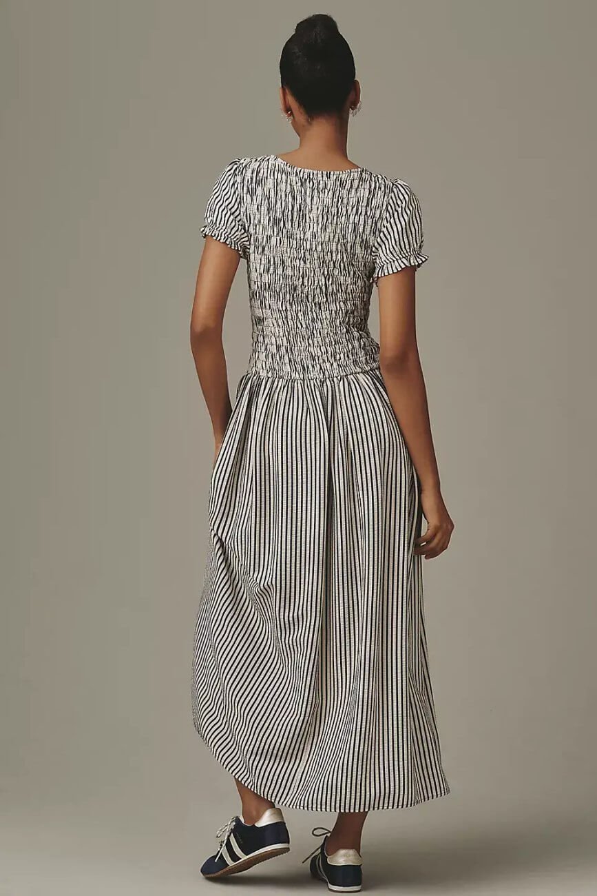 Back view of Model wearing Anthropologie Maeve Smoked Short Sleeve Maxi Dress, a striped short sleeve maxi dress with a gathered bodice