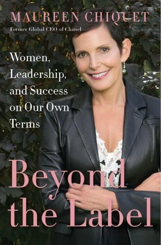 Book cover of “Beyond the Label” by Maureen Chiquet, former Global CEO of Chanel, showing a portrait of the author in a black leather jacket over a lace top, smiling against a dark green leafy backdrop, with the subtitle “Women, Leadership, and Success on Our Own Terms” and the title in bold pink lettering.