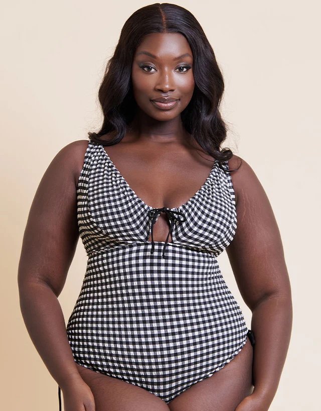A model wearing a Curvy Kate black and white gingham swimsuit, featured in a roundup of the best bikini brands for a fuller bust.