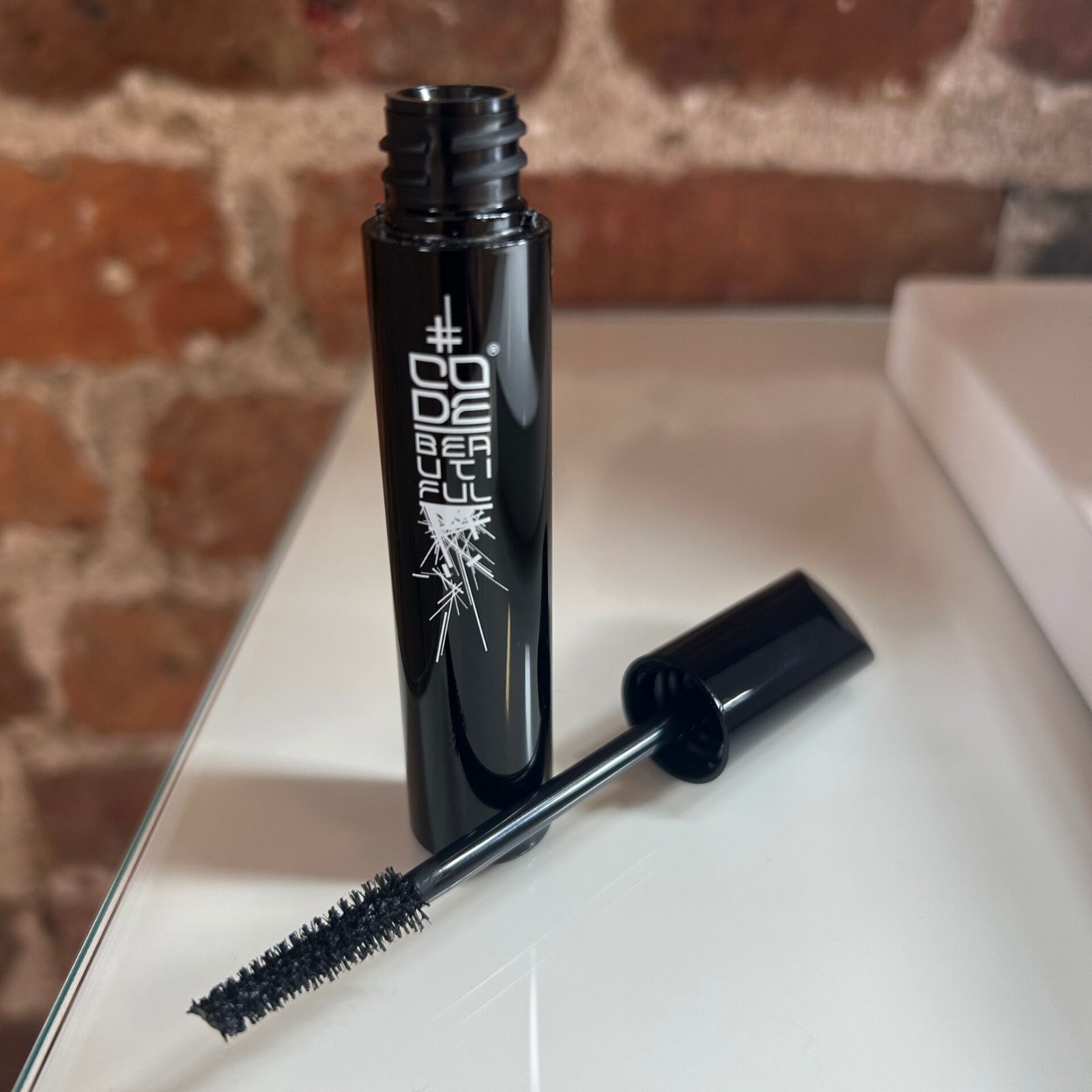 A black tube of VLM mascara with a textured wand, featuring the brand name 'CODE BEAUTIFUL' in white lettering