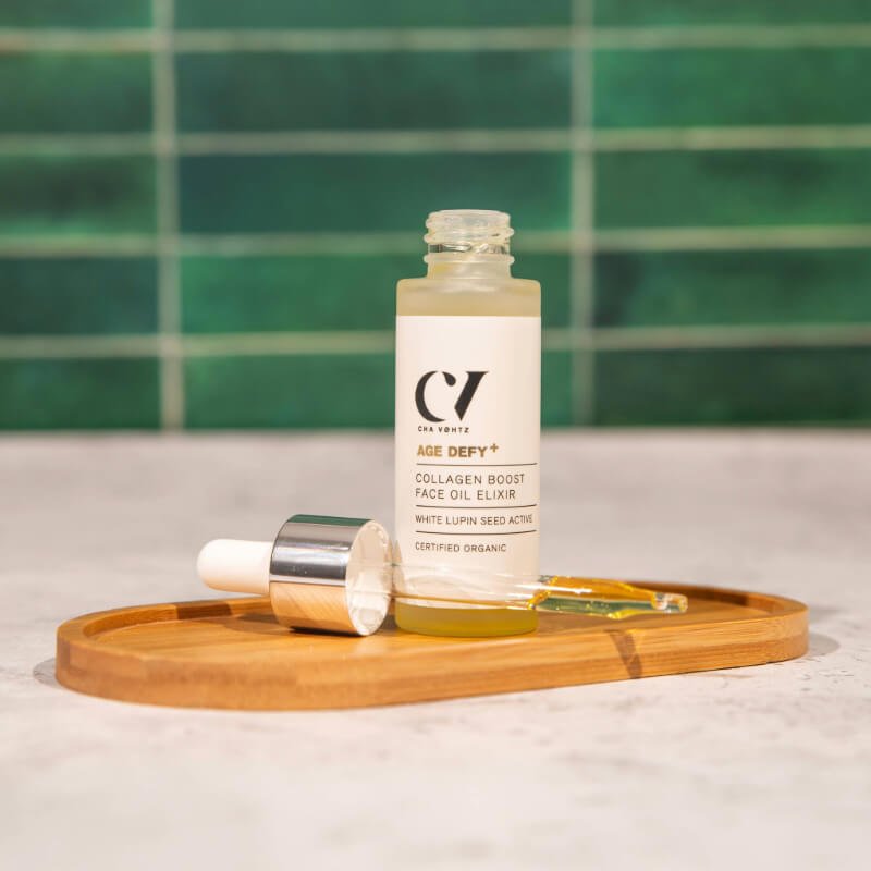 Green People Collagen boosting face oil elixir on a wooden tray with a dropper cap