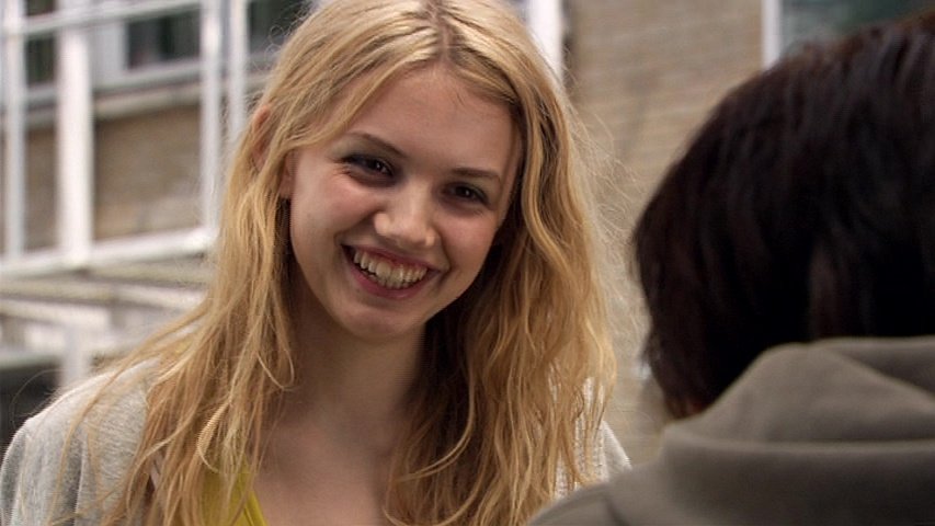 A close-up shot of Hannah Murray as Cassie Ainsworth in Skins, smiling widely with messy blonde hair while looking at someone out of frame.