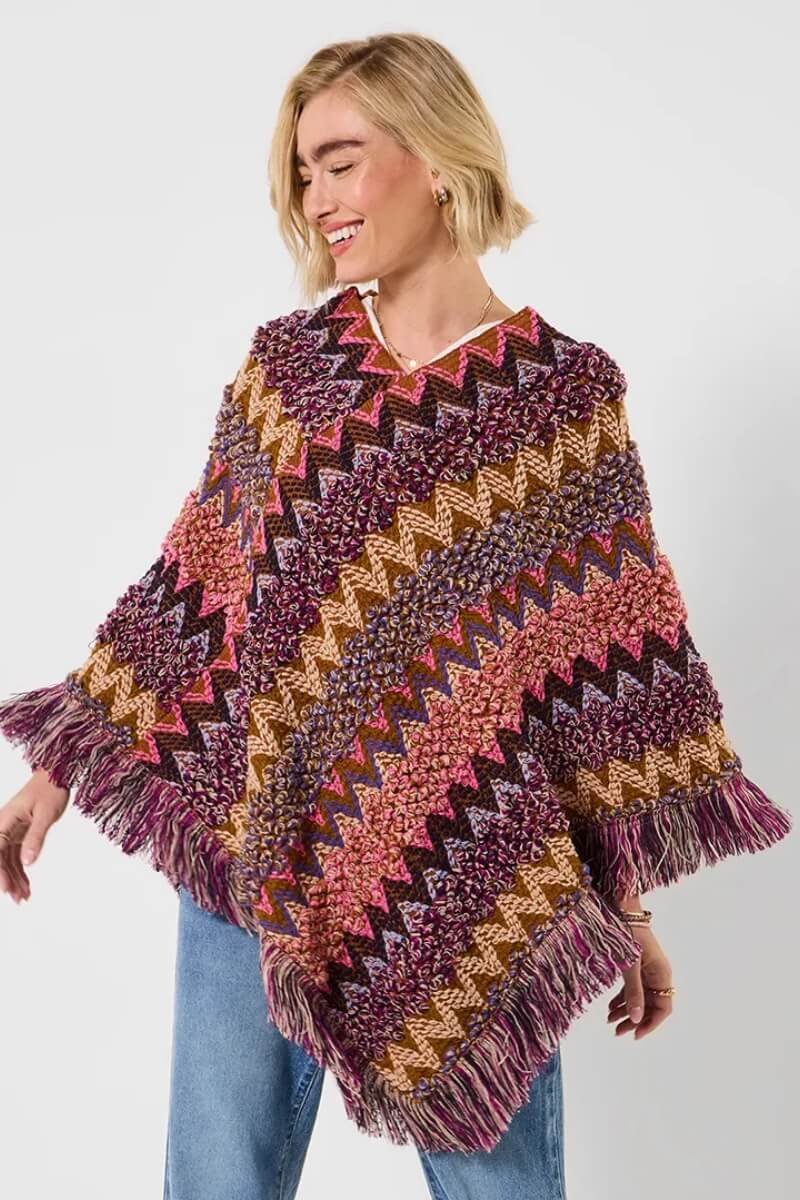 Model wearing Joe Browns multicolored knitted poncho with zigzag patterns and fringes