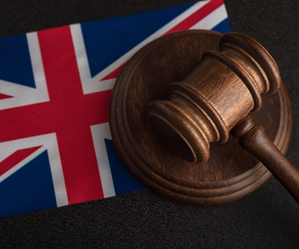 Close-up of a wooden judge's gavel resting on a sound block positioned on a Union Jack flag, illustrating the UK justice system as more than 200,000 people sign a petition calling for an investigation into Judge Nicholas Rowland after three boys convicted of rape walk free