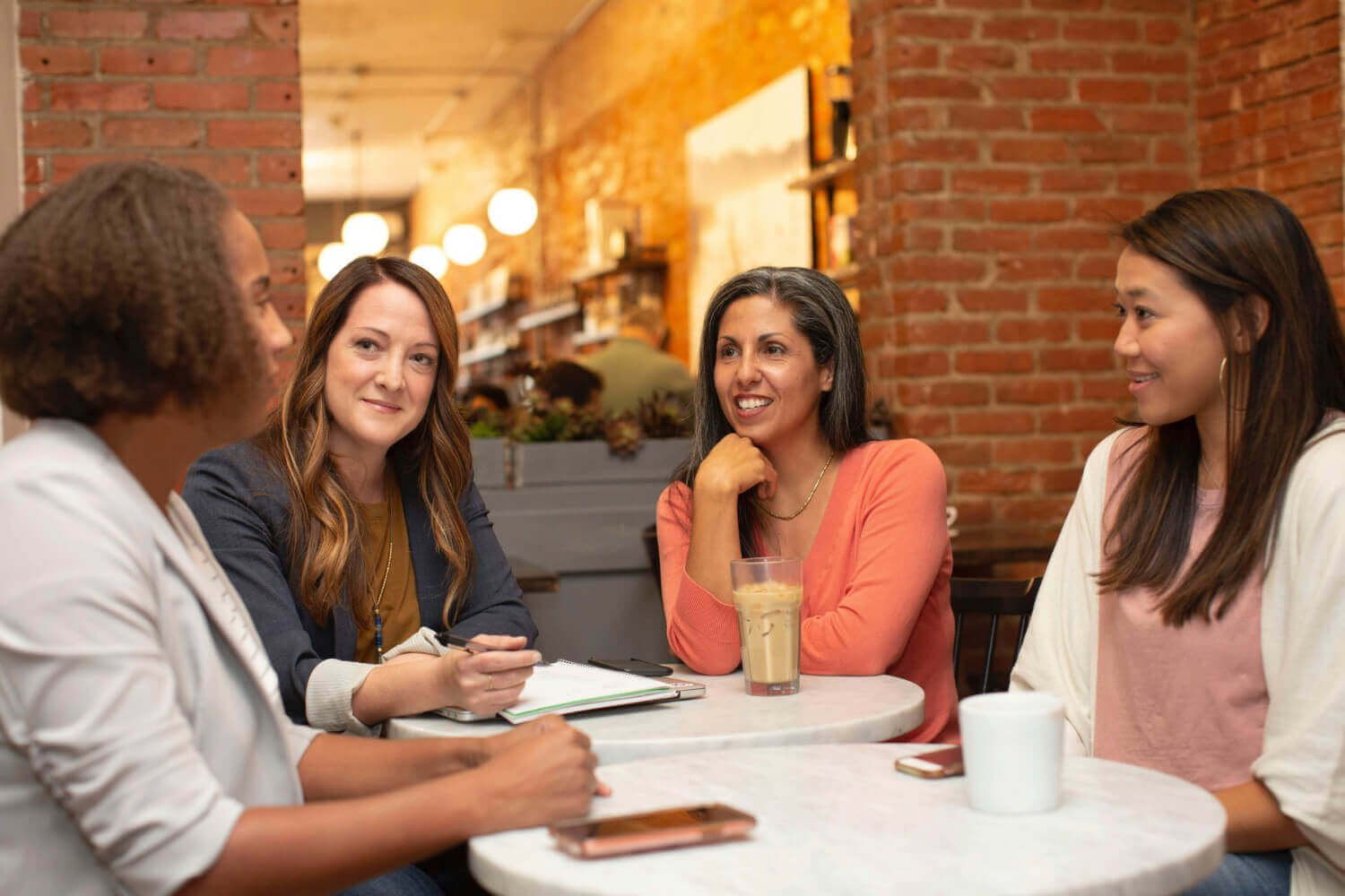 Group of women meeting in a café, engaging in conversation as part of a women-focused networking and career community