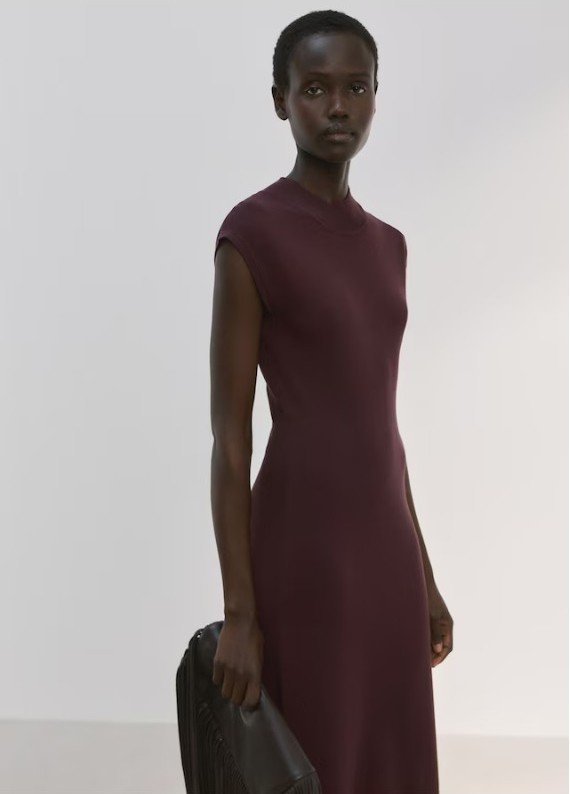 Model wearing Mango Perkins neck knitted dress in chocolate, a sleeveless, midi-length dress, paired with black shoes