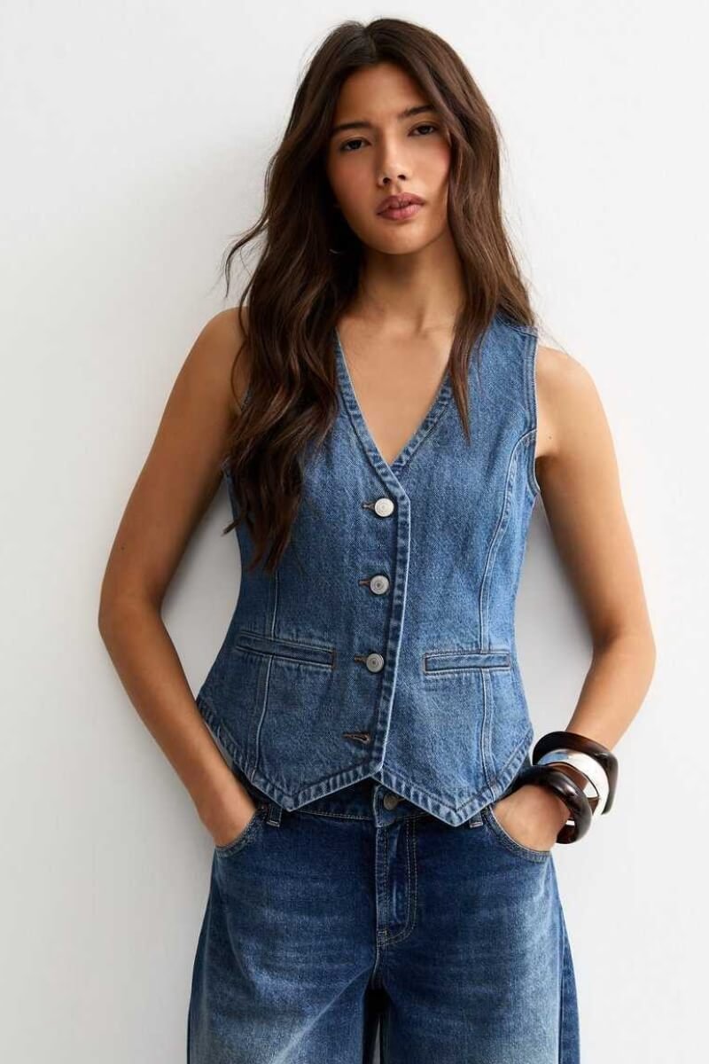 Model wearing New Look blue denim waistcoat with buttons and pockets, styled with wide-leg denim trousers
