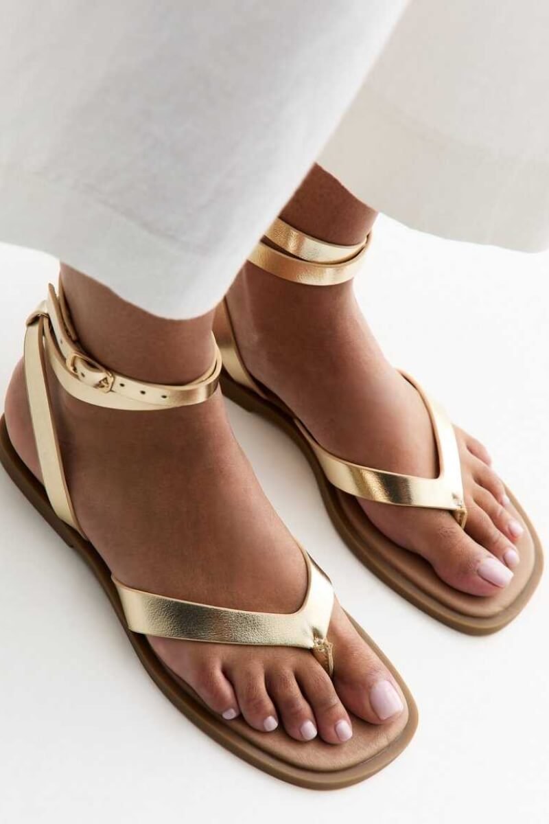 New Look gold ankle strap sandals with a toe post design worn on bare feet