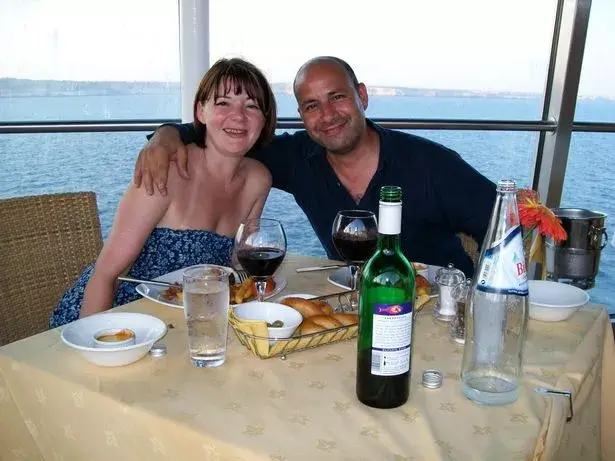 Nicky Wake wearing a blue strapless dress sitting beside her husband Andy at a seaside restaurant table with glasses of red wine before her sobriety journey