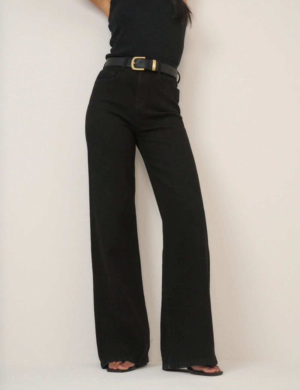 Up close view of a model wearing Nobody's Child black high rise soho wide leg jeans and a sleeveless black tank top