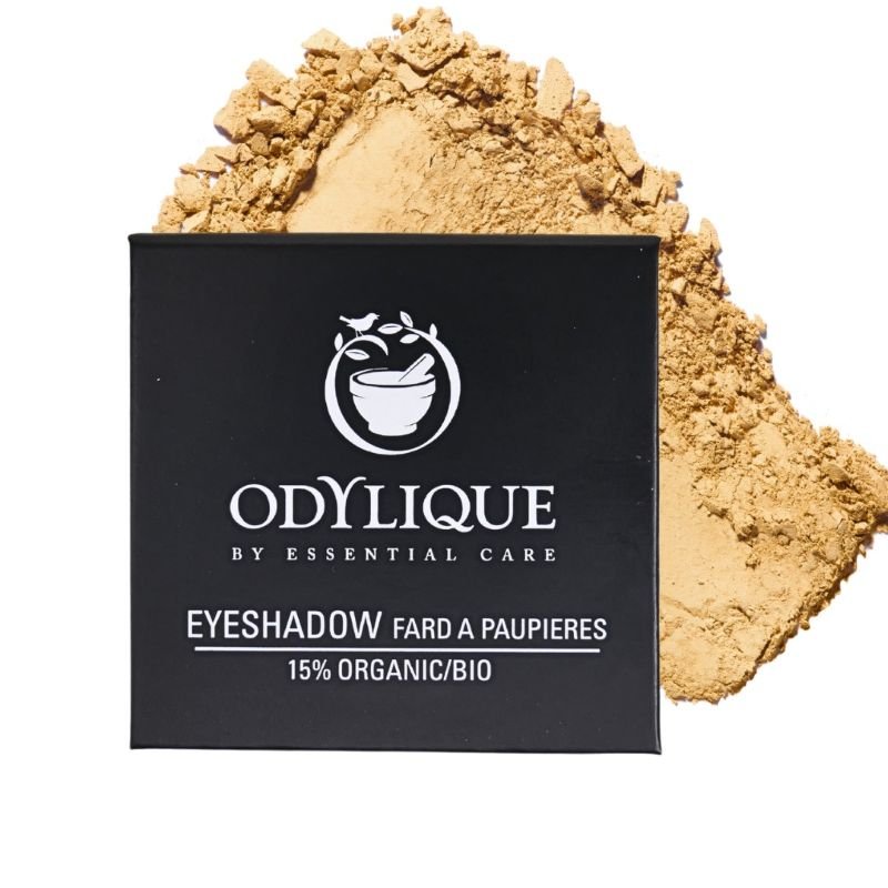 Odylique mineral eyeshadow in gold, with a box showing branding and loose powder scattered beside it