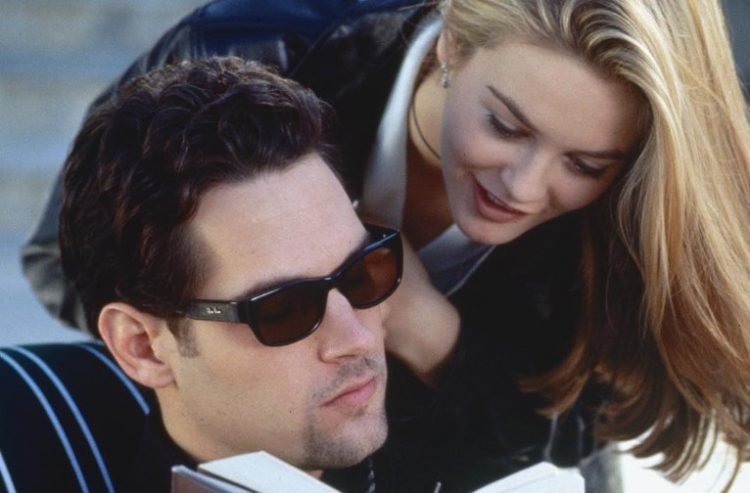 Paul Rudd as Josh, reading a book with his sunglasses on, while Alicia Silverstone as Cher leans onto his shoulder in a scene from 'Clueless'.