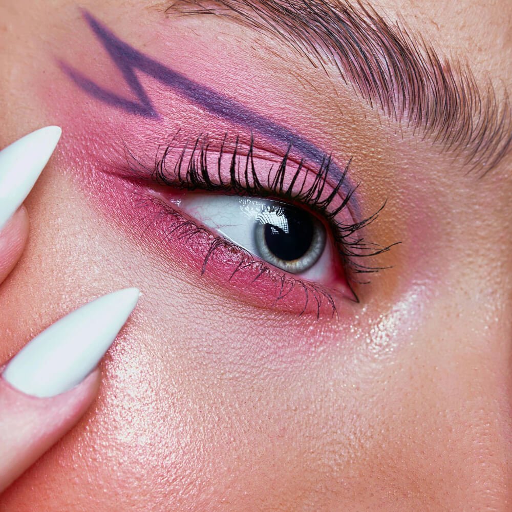Close-up of an eye with striking pink eyeshadow and a graphic purple eyeliner design