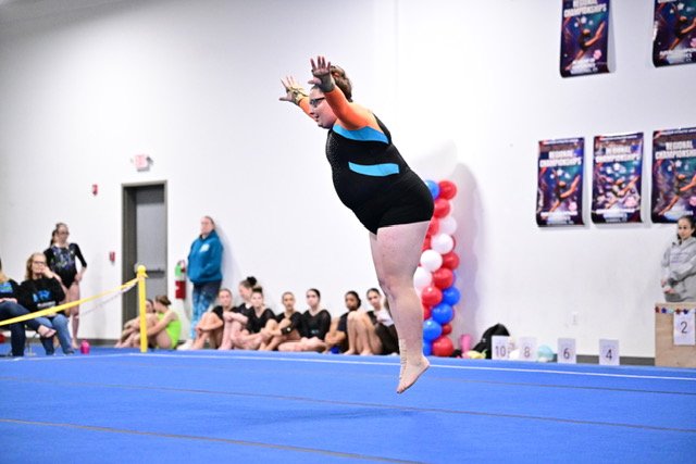 Plus-size gymnast Angela Salvatore jumps during her floor routine at a gymnastics competition.