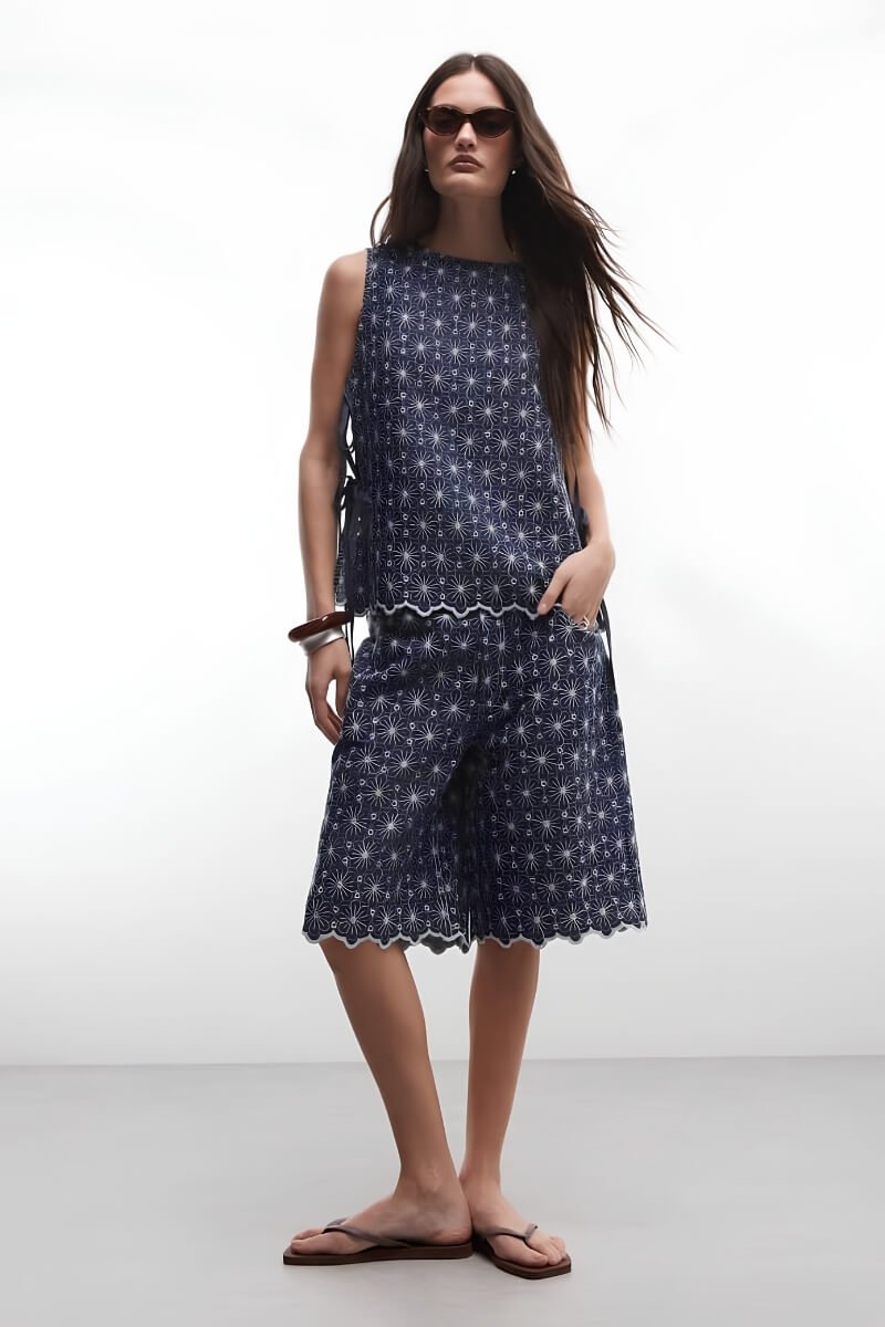 Model wearing Reclaimed Vintage navy chambray cutwork co-ord with floral patterns and flip-flops