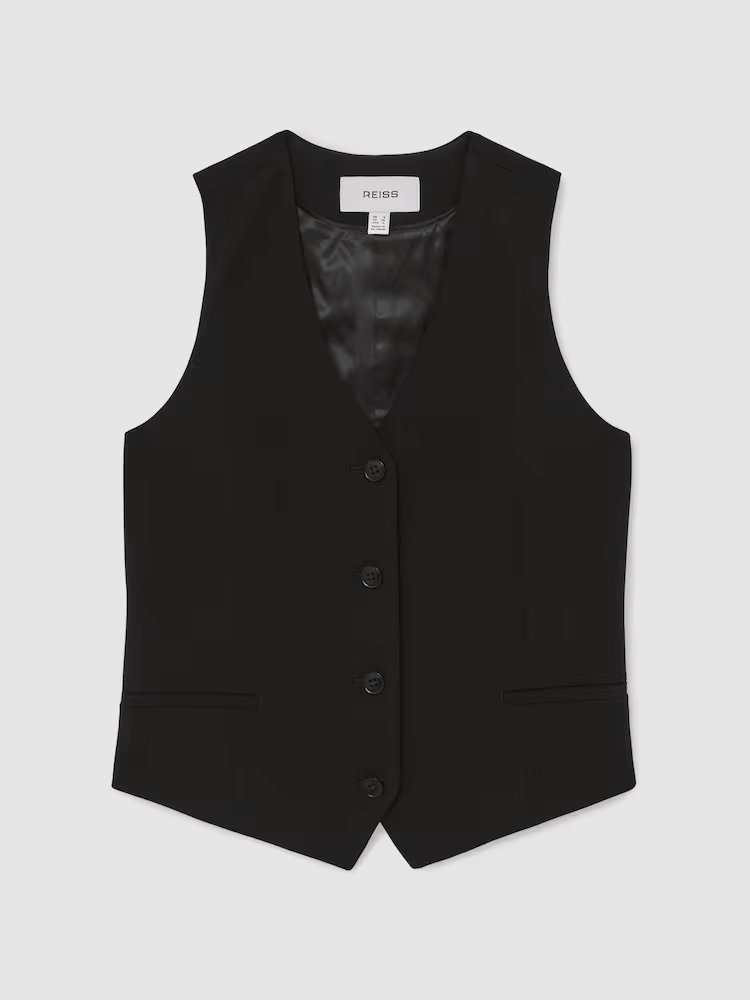 Front view of Gabi Single-Breasted Twill Waistcoat in Black, a fitted black vest and pants. The vest has a belt detail