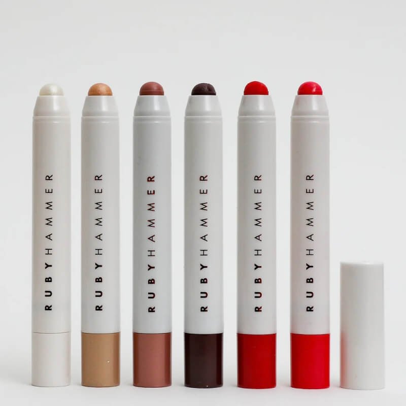 Set of six Ruby Hammer Beauty lip serum balm crayons in varying shades, arranged on a white background