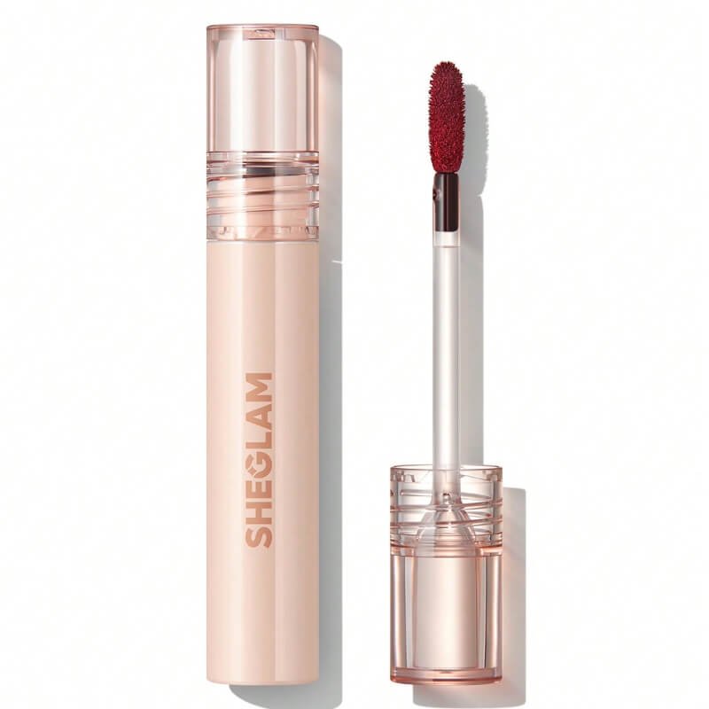 A SHEGLAM lip stain in a clear tube with a red applicator wand, showcasing a cherry-bark shade