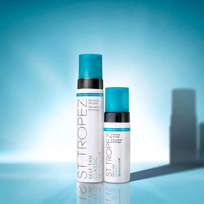 Two bottles of St. Tropez Classic Bronzing Mousse against a soft blue background