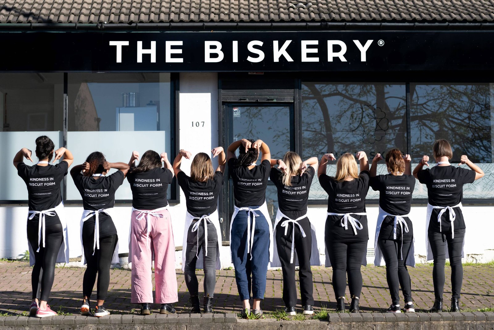 The women-led team at The Biskery standing outside the Leeds bakery wearing 'Kindness in Biscuit Form' t-shirts, highlighting the company’s flexible working culture for mothers