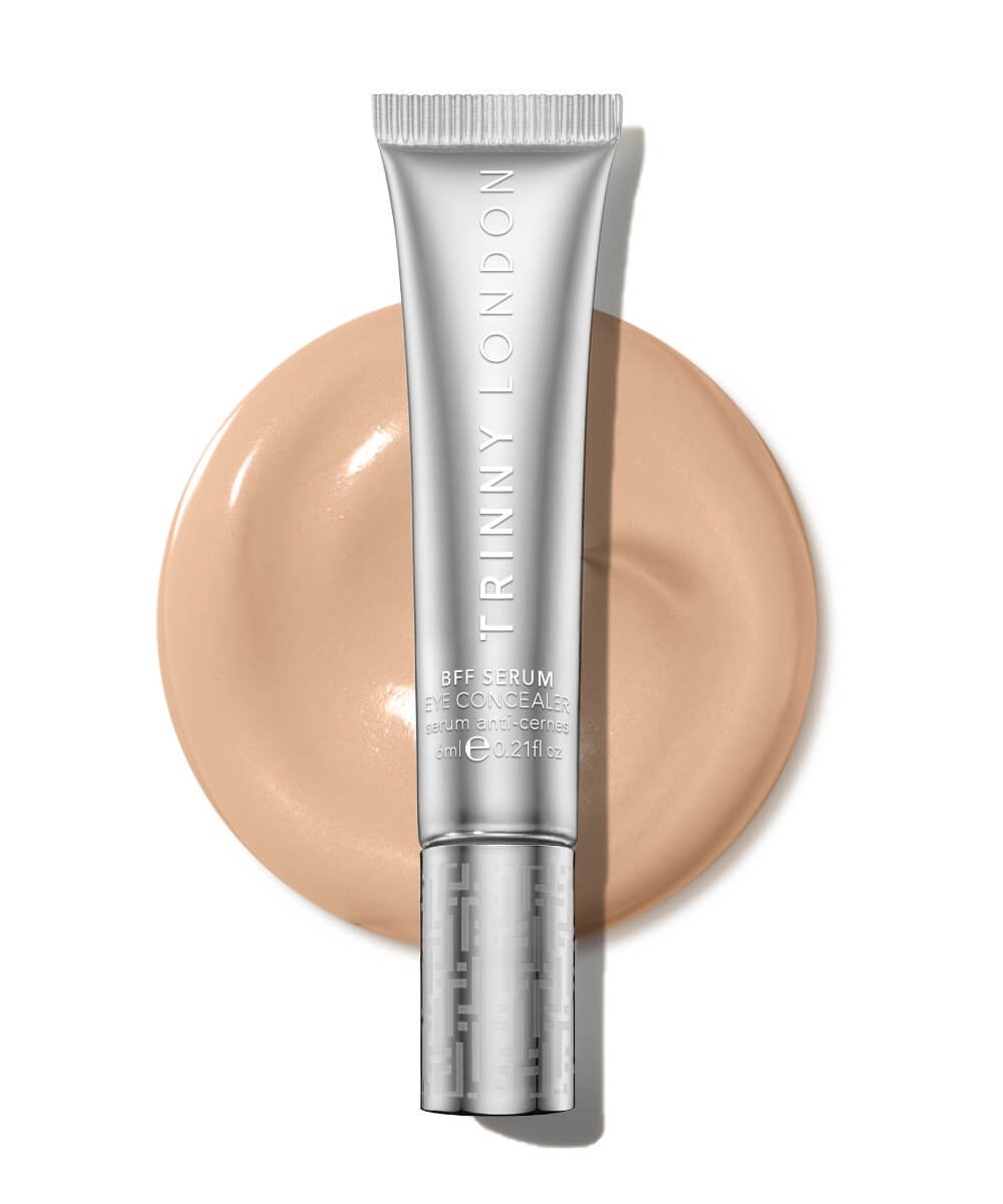Trinny London BFF Eye Serum Concealer tube beside a creamy beige swatch on a white background