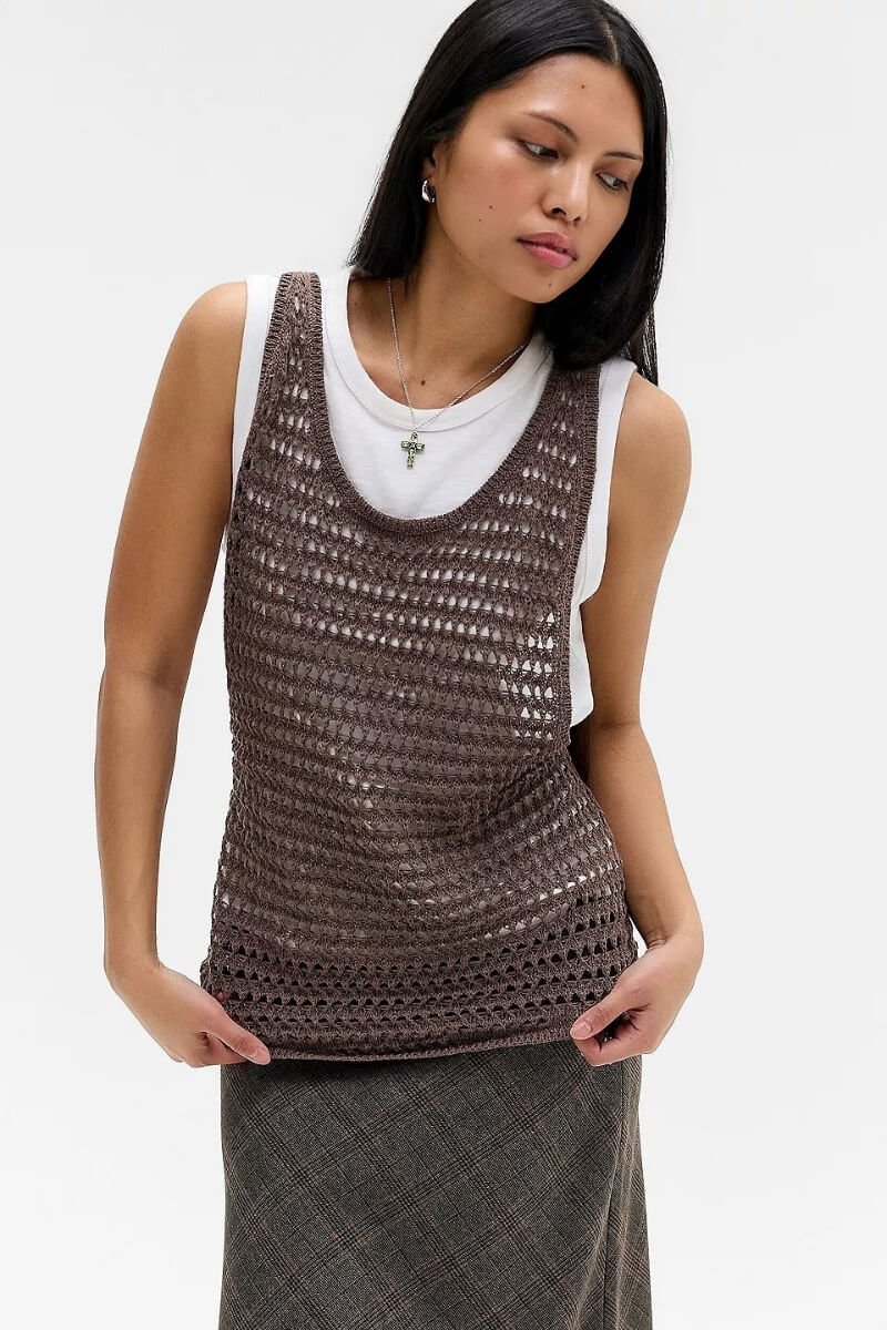 A model wearing UO Cleo brown crochet tank top over a white shirt, paired with a skirt