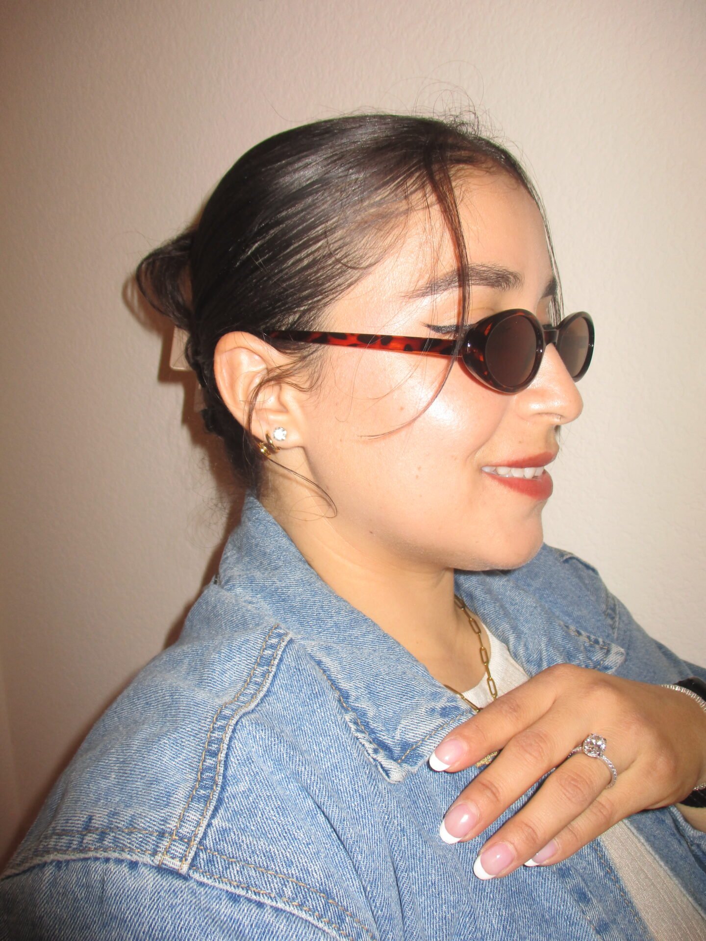 Woman with a sleek low bun wearing tortoiseshell sunglasses and a denim jacket