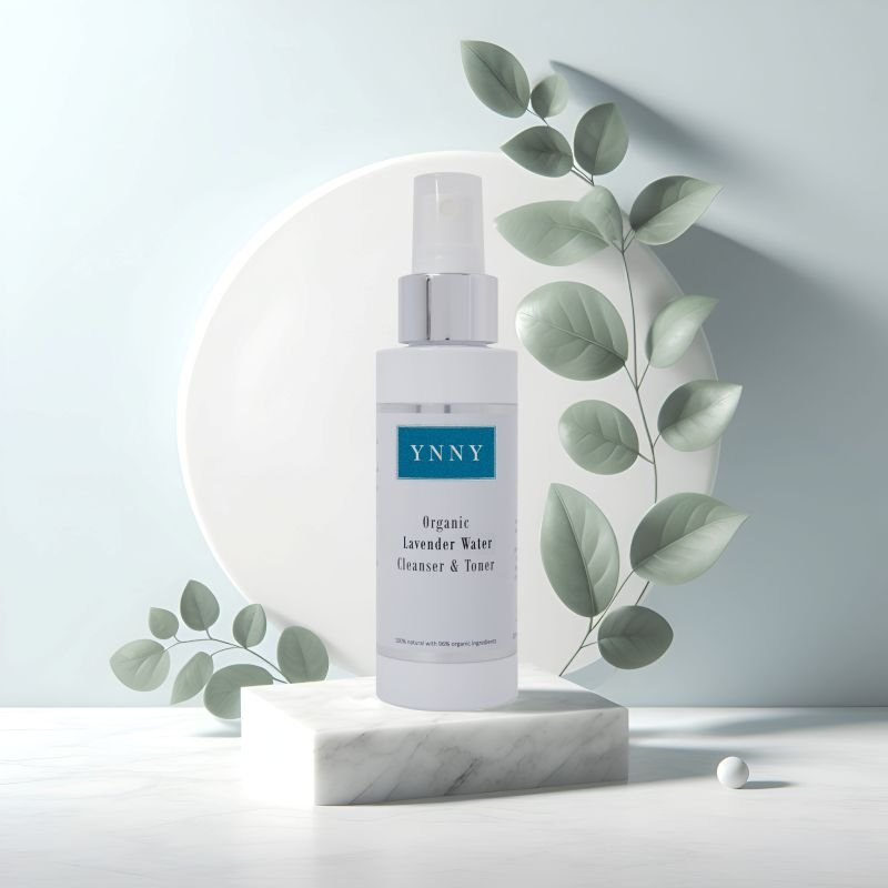 A white bottle of YNNY Organic Lavender Water Cleanser & Toner on a marble pedestal surrounded by soft green leaves