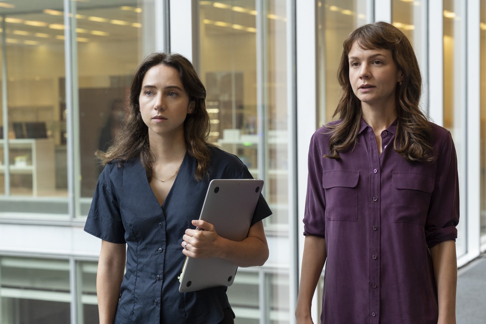 Zoe Kazan as Jodi Cantor holding a computer while walking next to Carey Mulligan as Megan Twohey in a scene from 'She Said'.